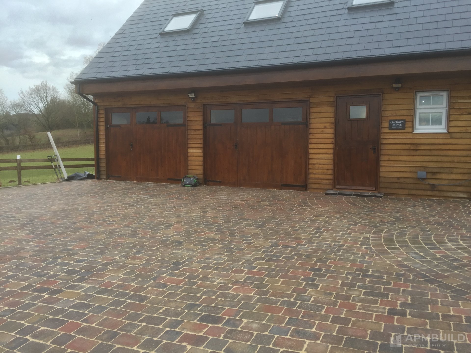 Completed twin-garage with larch shiplap cladding, slate roof and sett-paver drive in Foy Ross-on-Wye by APMBuild, Herefordshire