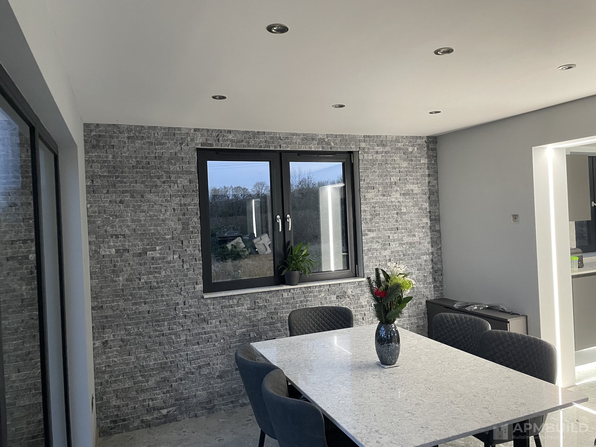 Completed dining area with split-stone feature wall and quartz table in Gorsley extension by APMBuild, Herefordshire