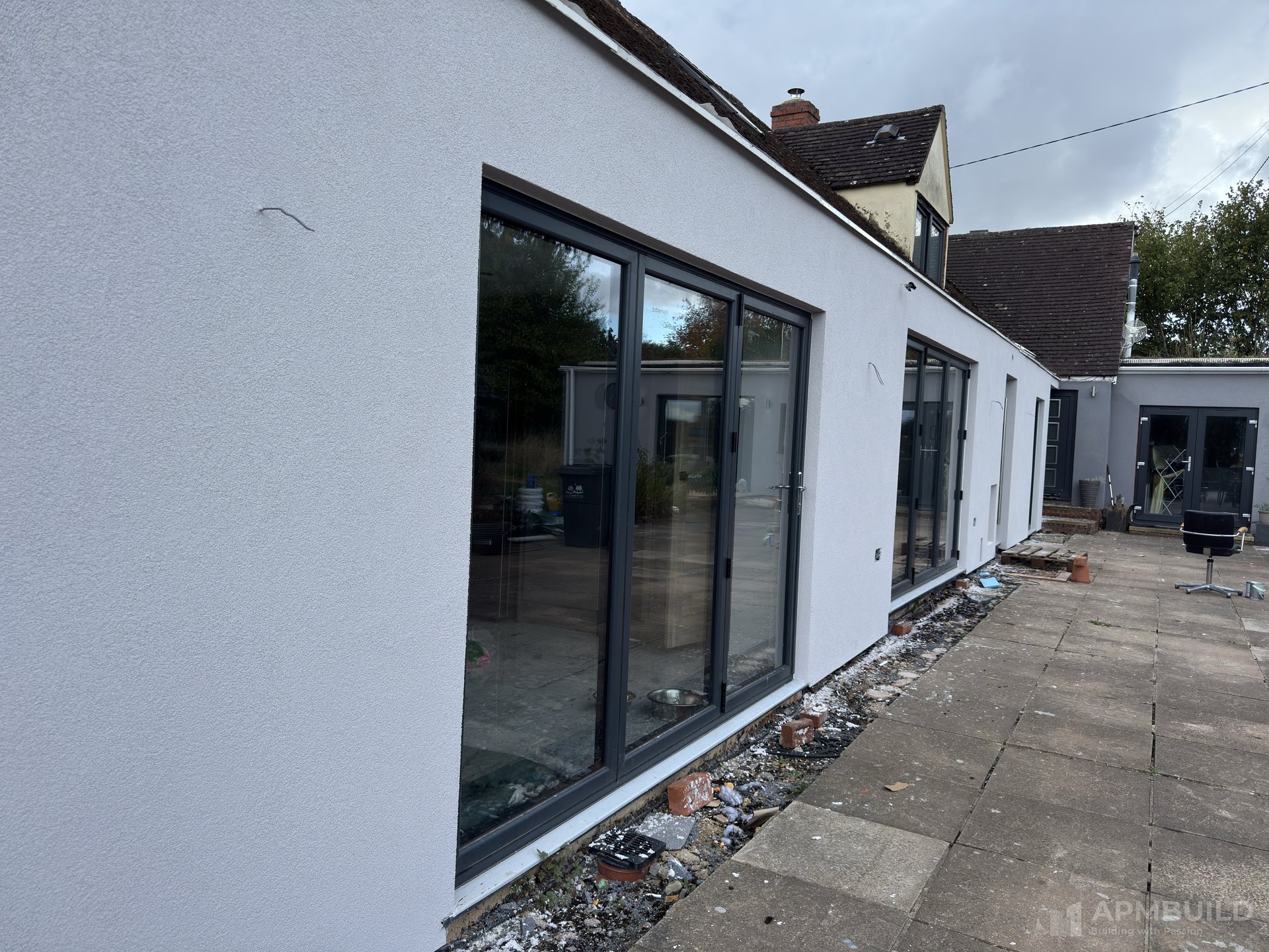 Completed rendered rear extension with full-width aluminium bi-fold doors in Gorsley by APMBuild, Herefordshire