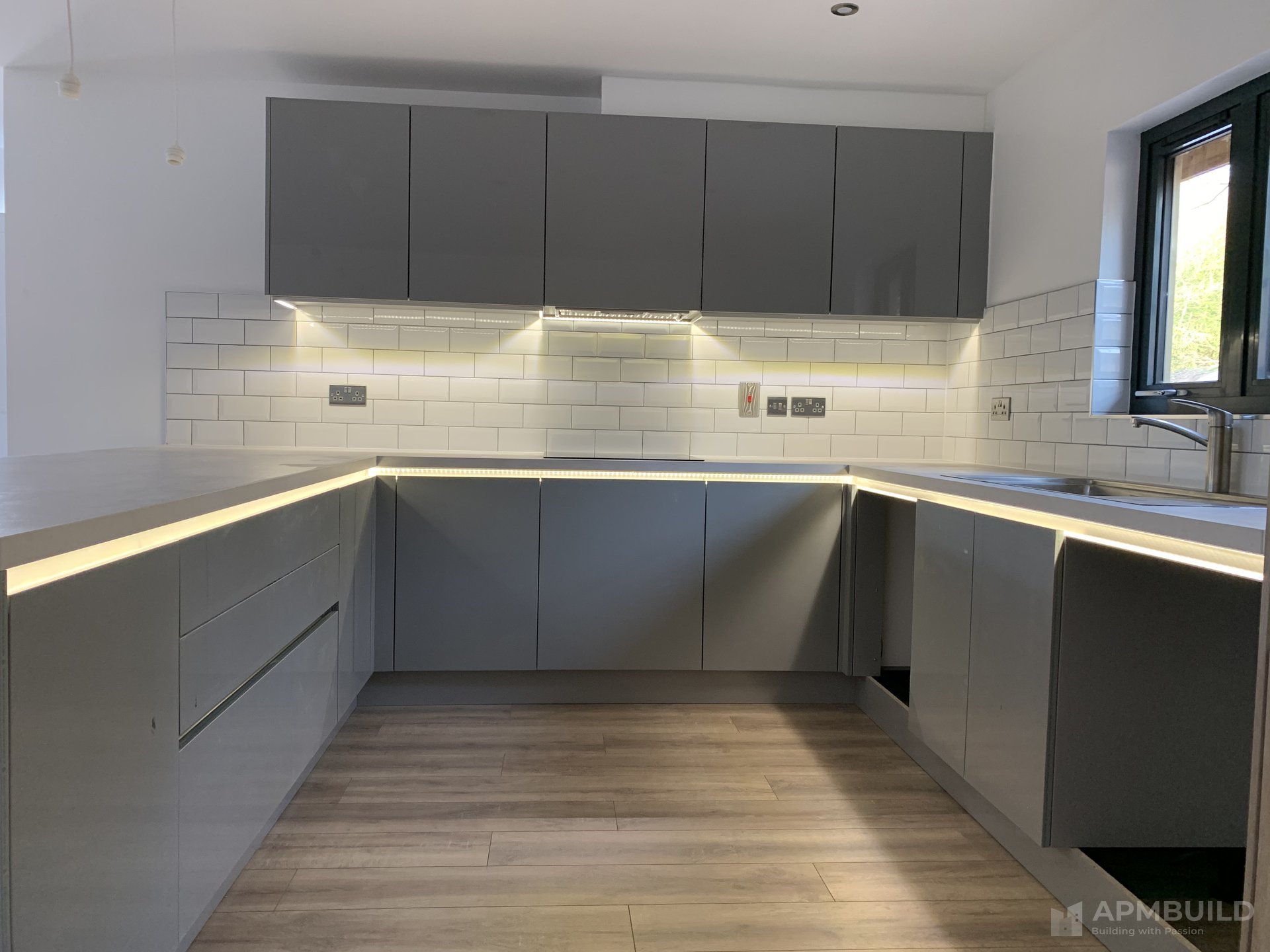 Completed grey shaker kitchen with white subway tile backsplash and LED under-cabinet lighting in Hole in the Wall Ross-on-Wye by APMBuild