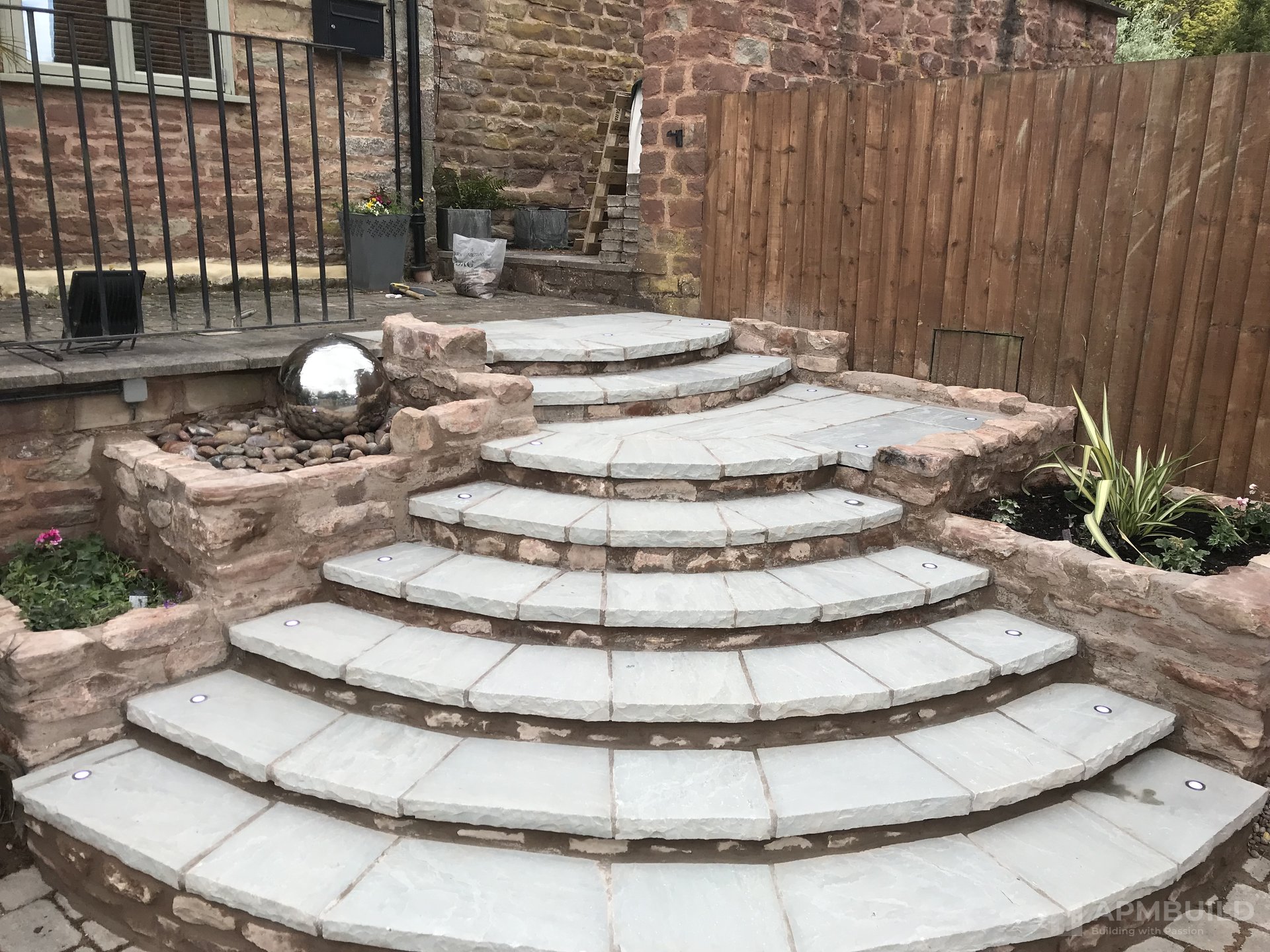 Completed curved sandstone front steps with stainless sphere planters in Lea Ross-on-Wye by APMBuild, Herefordshire