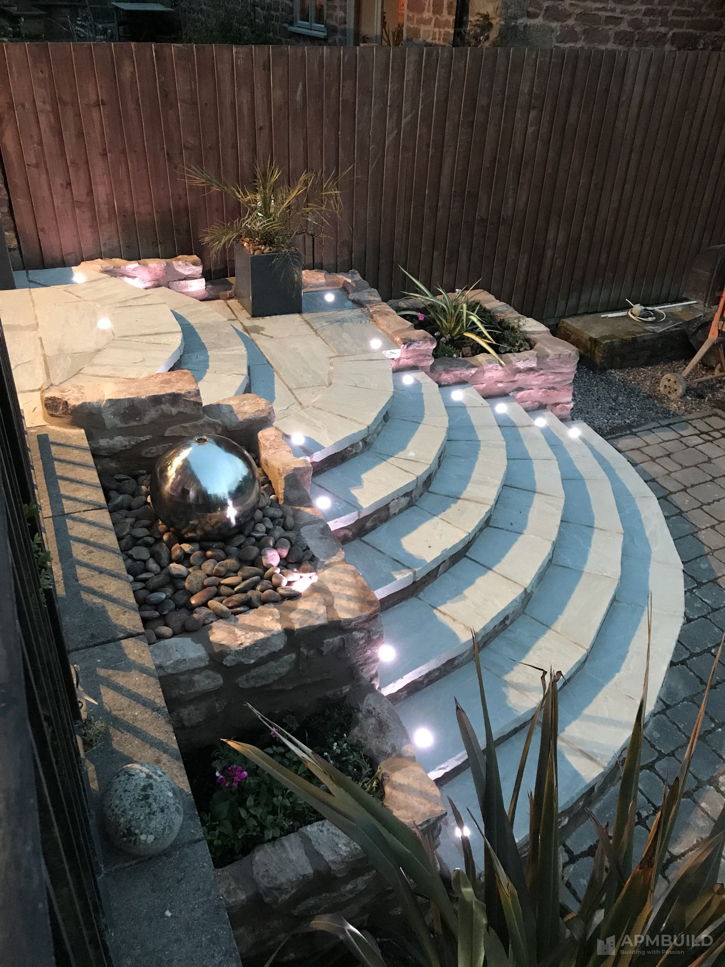 Night view of curved sandstone steps with uplighting in Lea Ross-on-Wye by APMBuild, Herefordshire