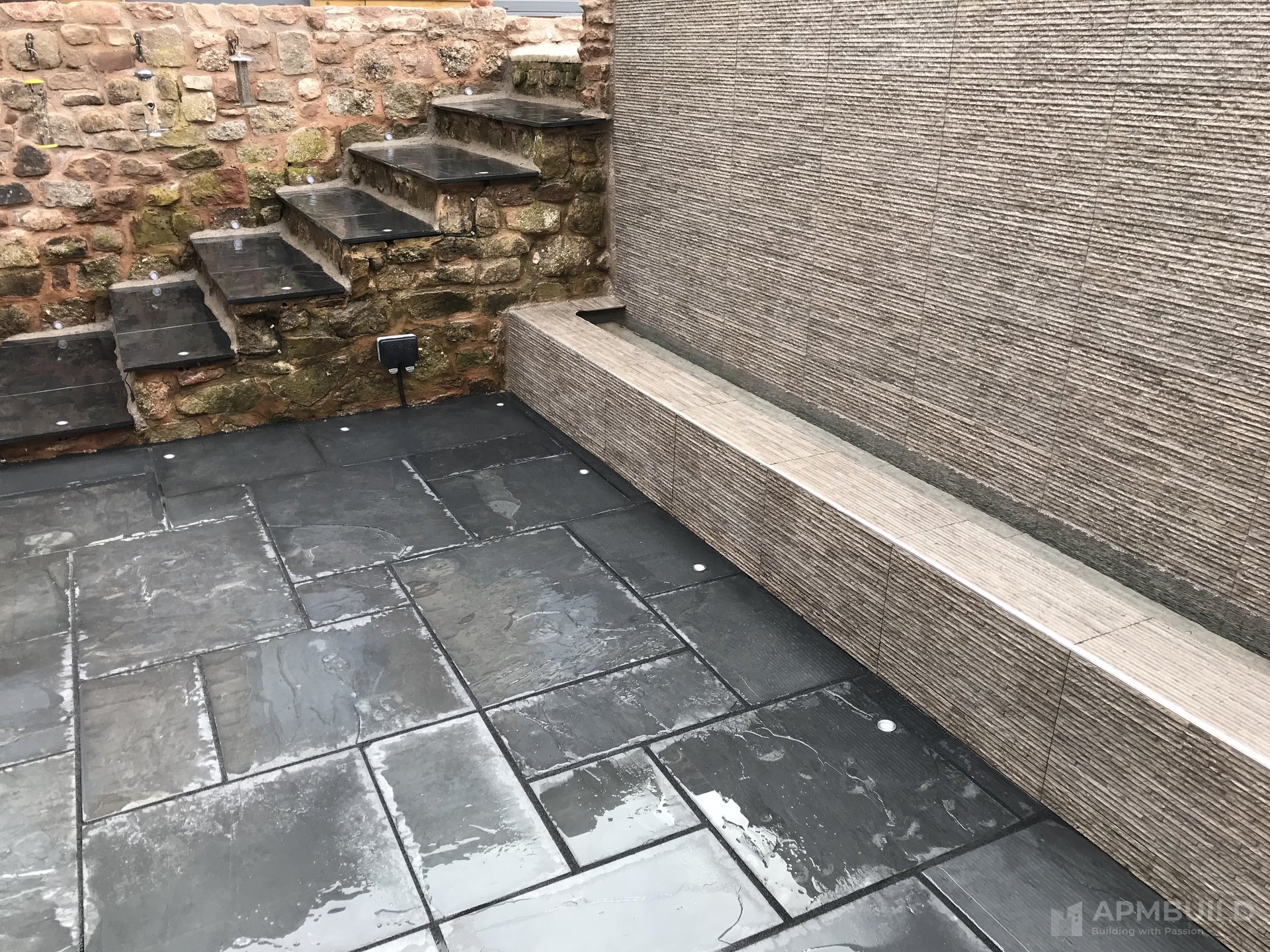 Backlit blue-LED water feature wall in Lea Ross-on-Wye garden by APMBuild, Herefordshire