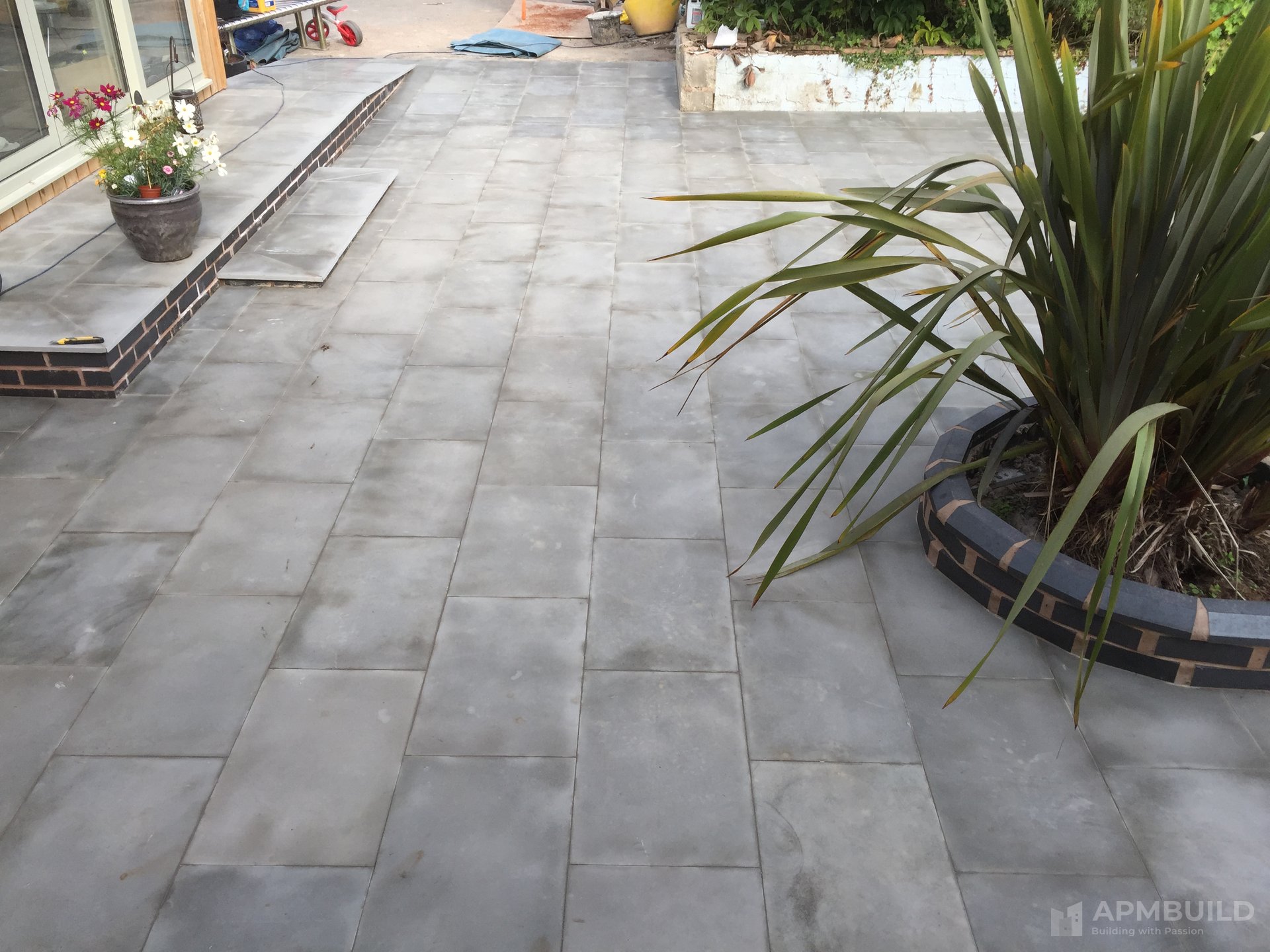 Completed stone-flag patio with brick-edged planter in Putley garden by APMBuild, Herefordshire