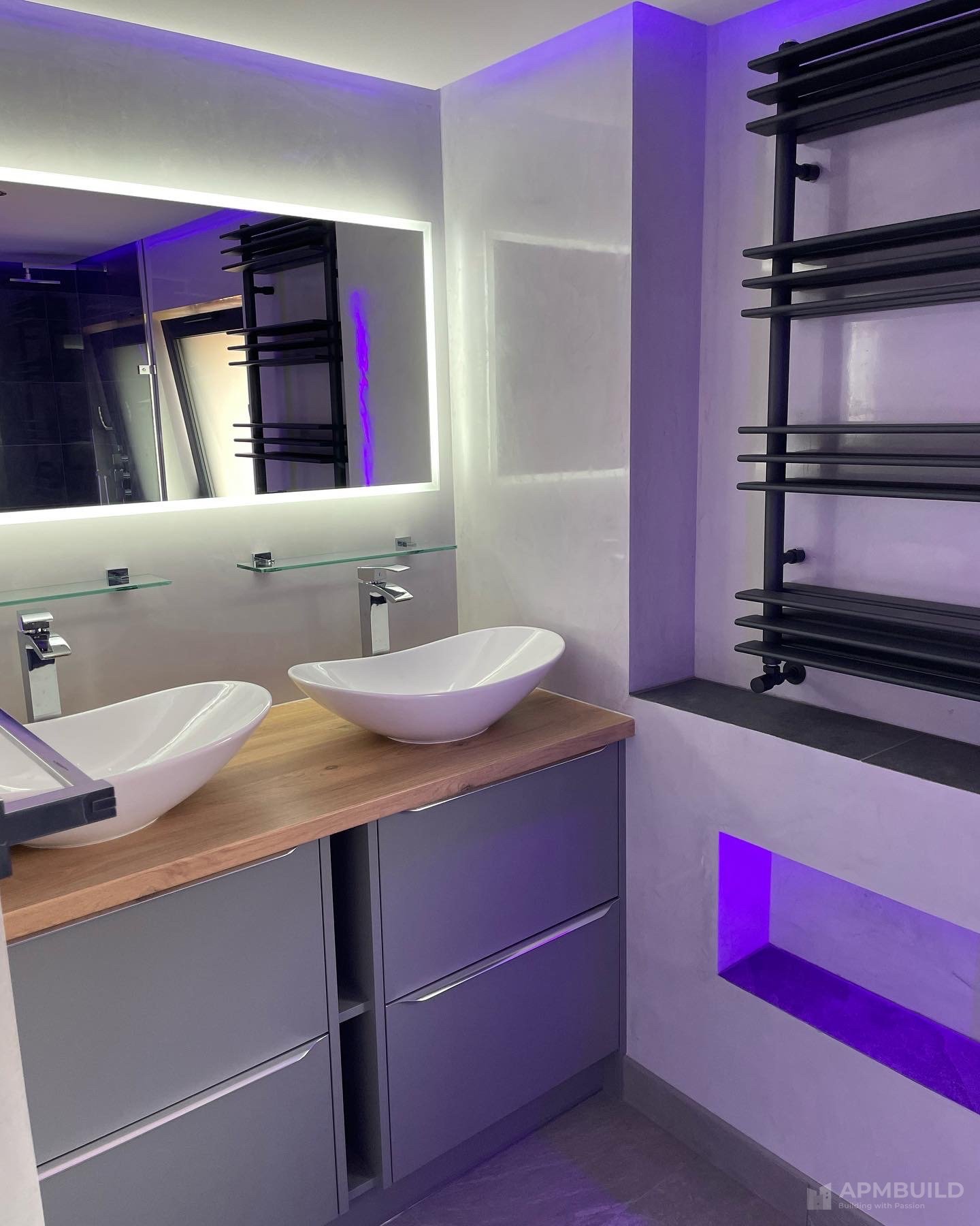 Completed ensuite with vessel sinks on oak vanity, illuminated mirror and purple LED niche in Saxon Gate Hereford by APMBuild