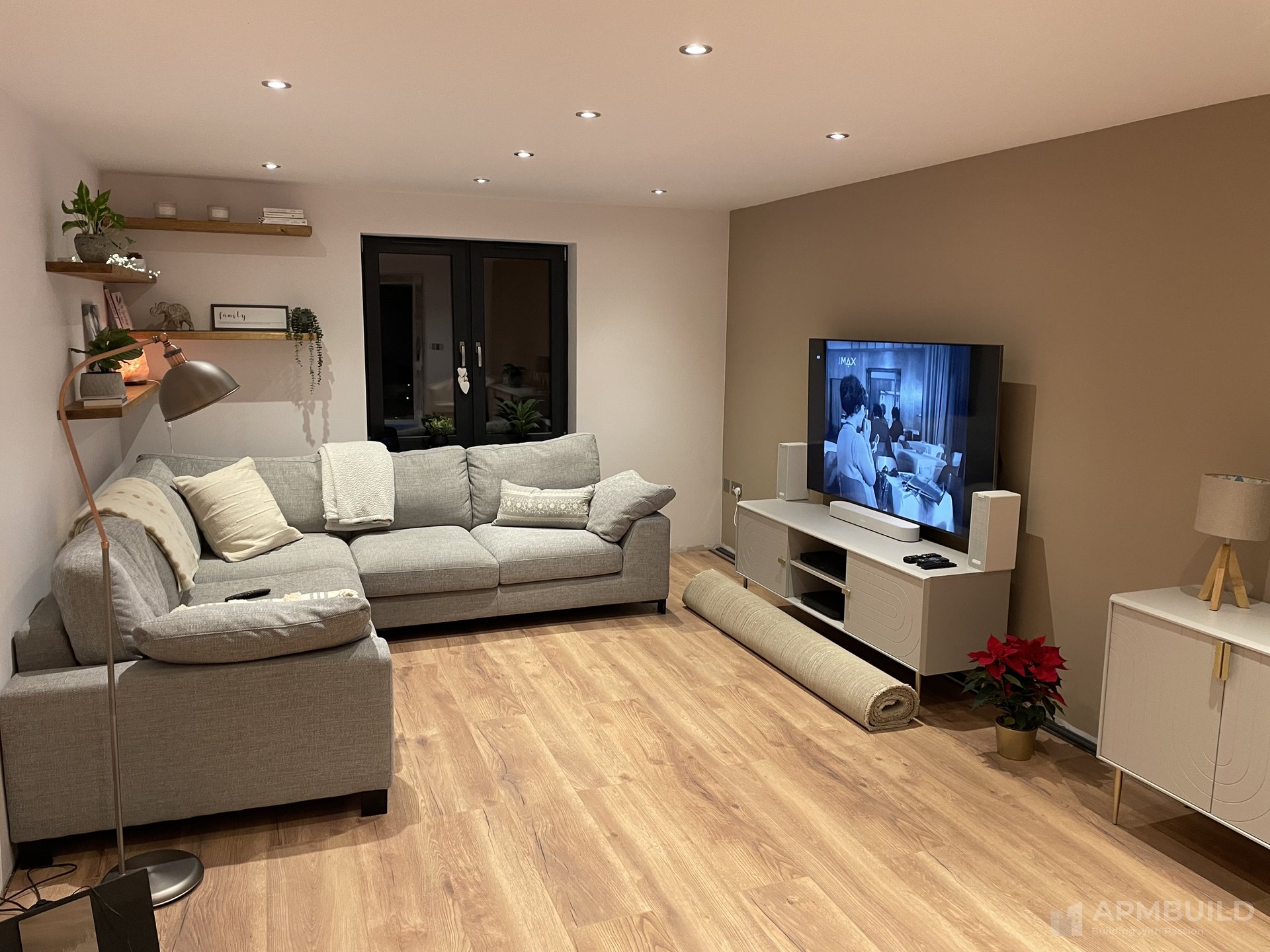 Completed open lounge with engineered oak floor, corner sofa and floating shelves in Saxon Gate Hereford by APMBuild